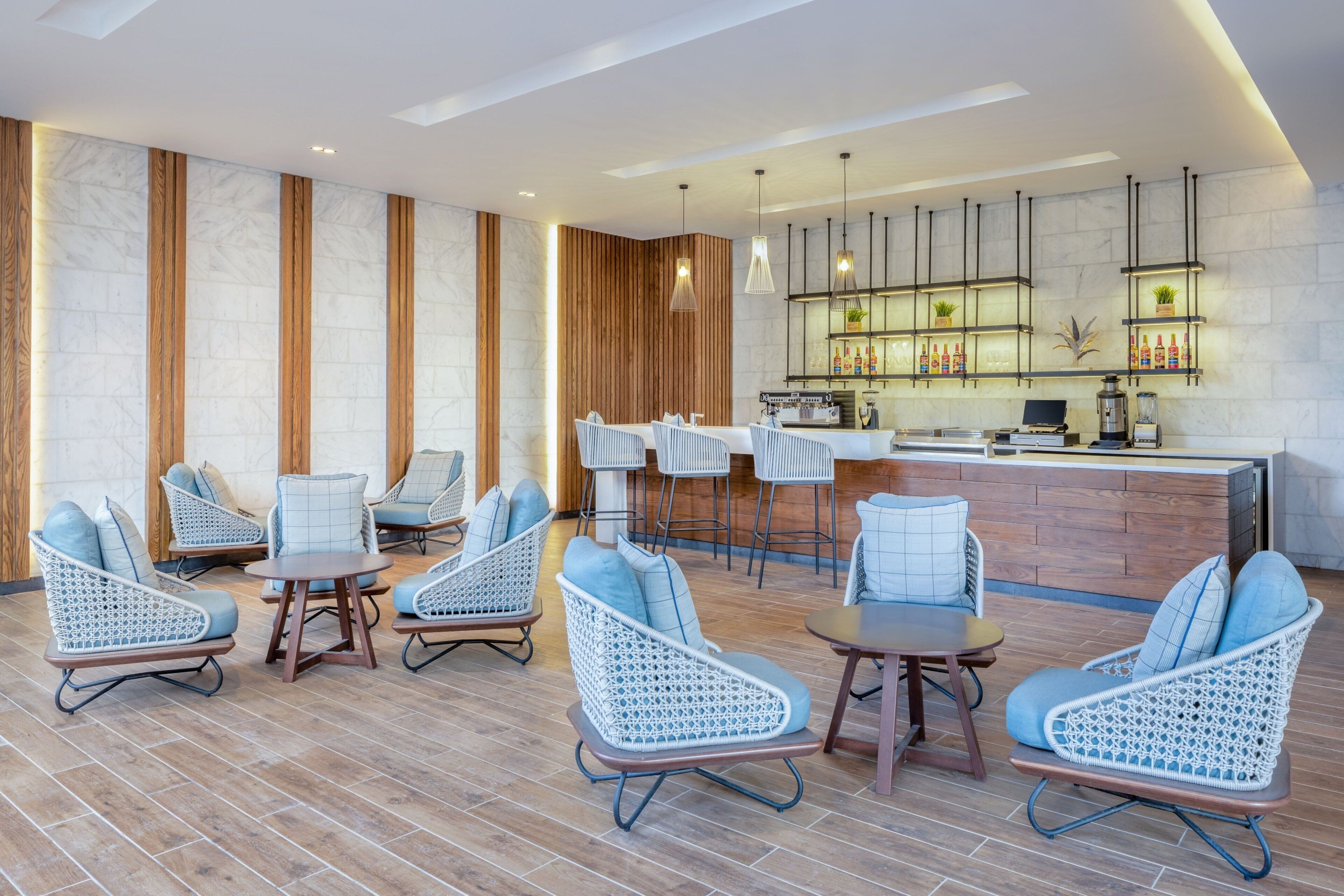 Un área de descanso moderna con sillones de mimbre, bar y un revestimiento de pared de madera.