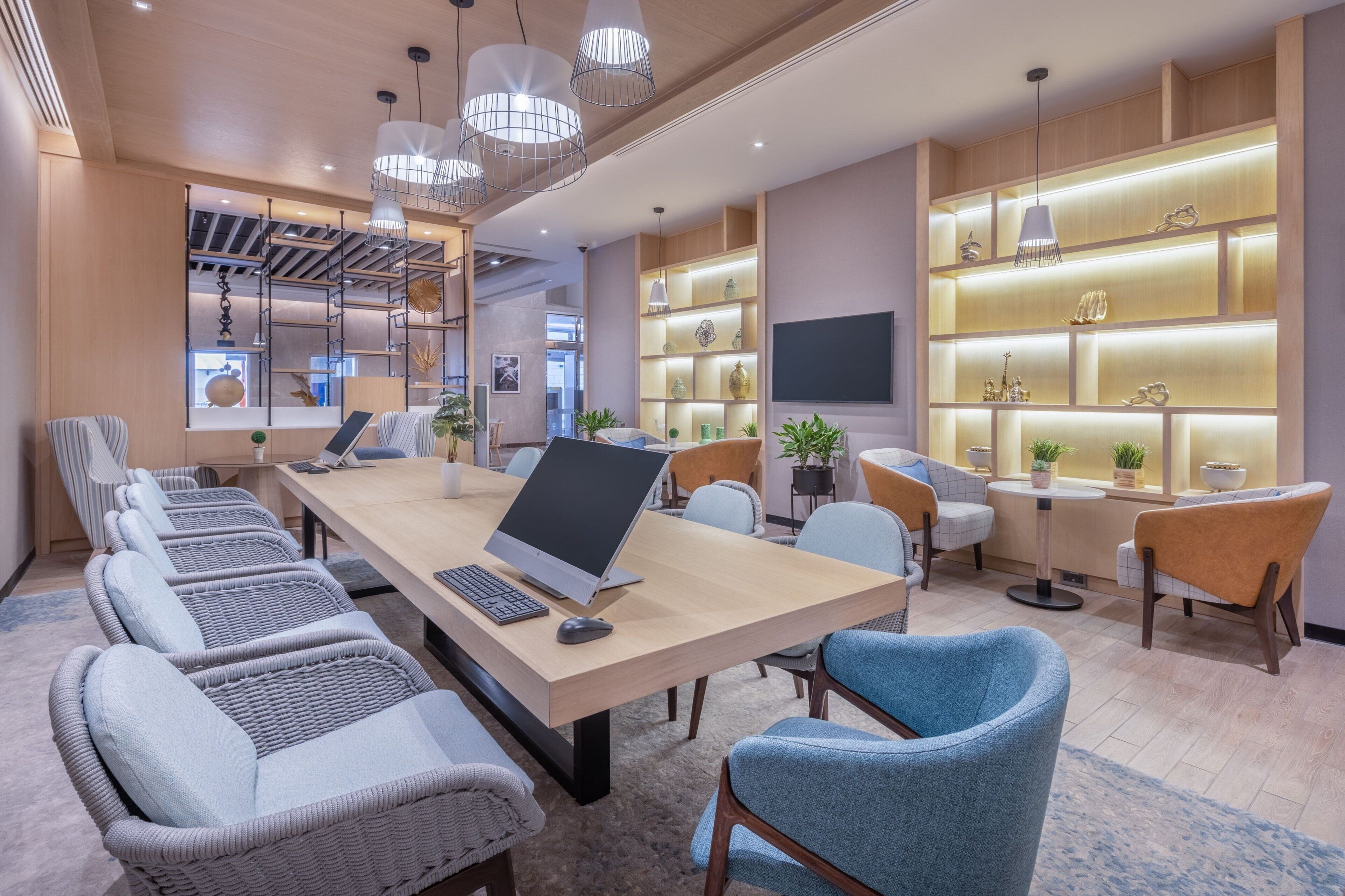 A modern conference room with a long table, multiple chairs, and a laptop.