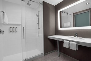A modern bathroom with a glass-enclosed shower, a white sink with a mirror above it, and two towels hanging on the wall. - AC Hotel by Marriott Washington DC Capitol Hill Navy Yard (Washington)