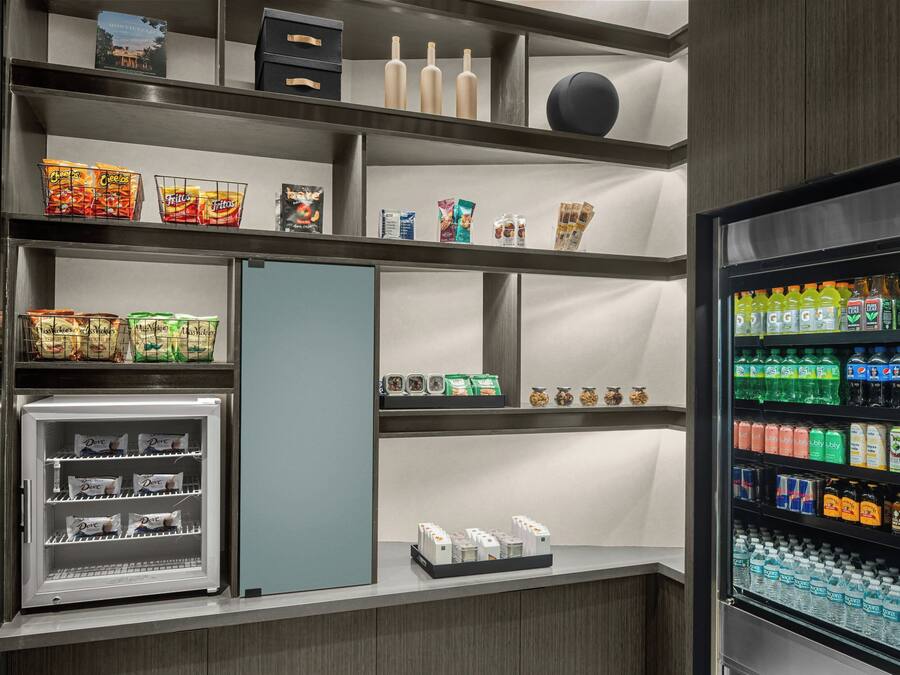 Zona de exhibición de aperitivos y bebidas bien organizada, con diversas opciones de comida, refrescos y un refrigerador.