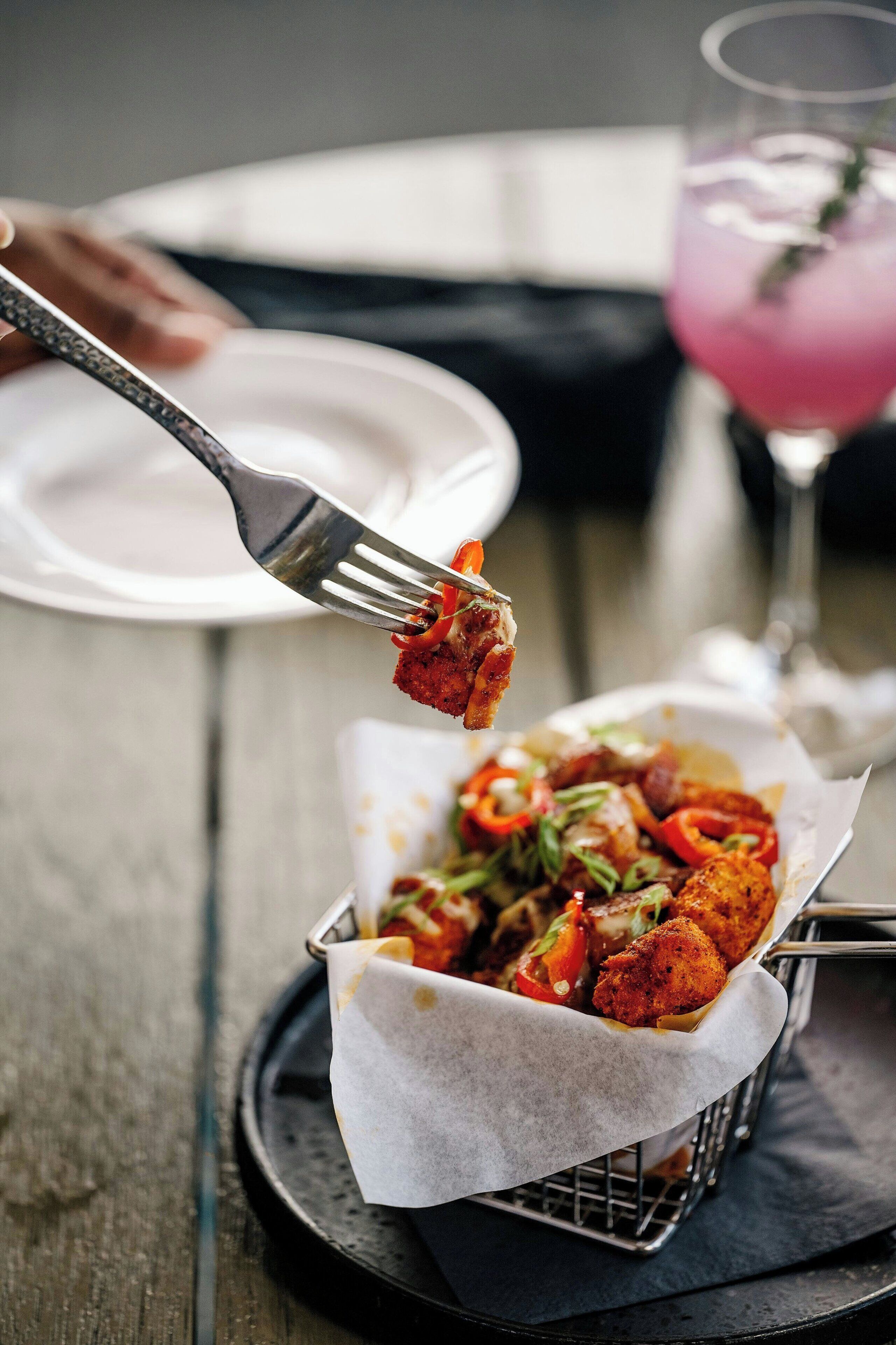 A basket of food on a table with a fork lifting a piece of food.