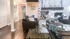 A modern living room with a fireplace, dark leather sofas, and a star-shaped coffee table. - THE FAMILY FOREST · ★3 Acres Of Forest★Lighted Yard★Chef Kitchen★ (Colorado Springs)