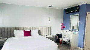 A modern hotel room with a large bed, a bedside table, a small desk with a chair, a bathroom with a mirror, and an air conditioning unit. - Bushiri's Long Life Studio w/Kingbed & Balcony #5 (Oranjestad)