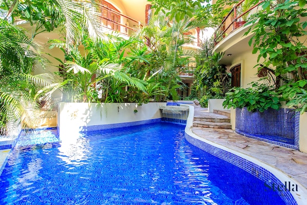 Relax by the serene pool surrounded by lush tropical plants and enjoy a picturesque view.