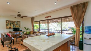 Un'ampia zona giorno con un'isola centrale, una ventola a soffitto, una televisione e un'area pranzo con sedie e tavolo.