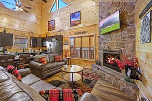 A spacious living area with a fireplace, leather furniture, and a stone accent wall. - Private Indoor Pool + Hot Tub · 4BR/4BA · Sleeps 10 · Minutes to Dollywood (Pigeon Forge)