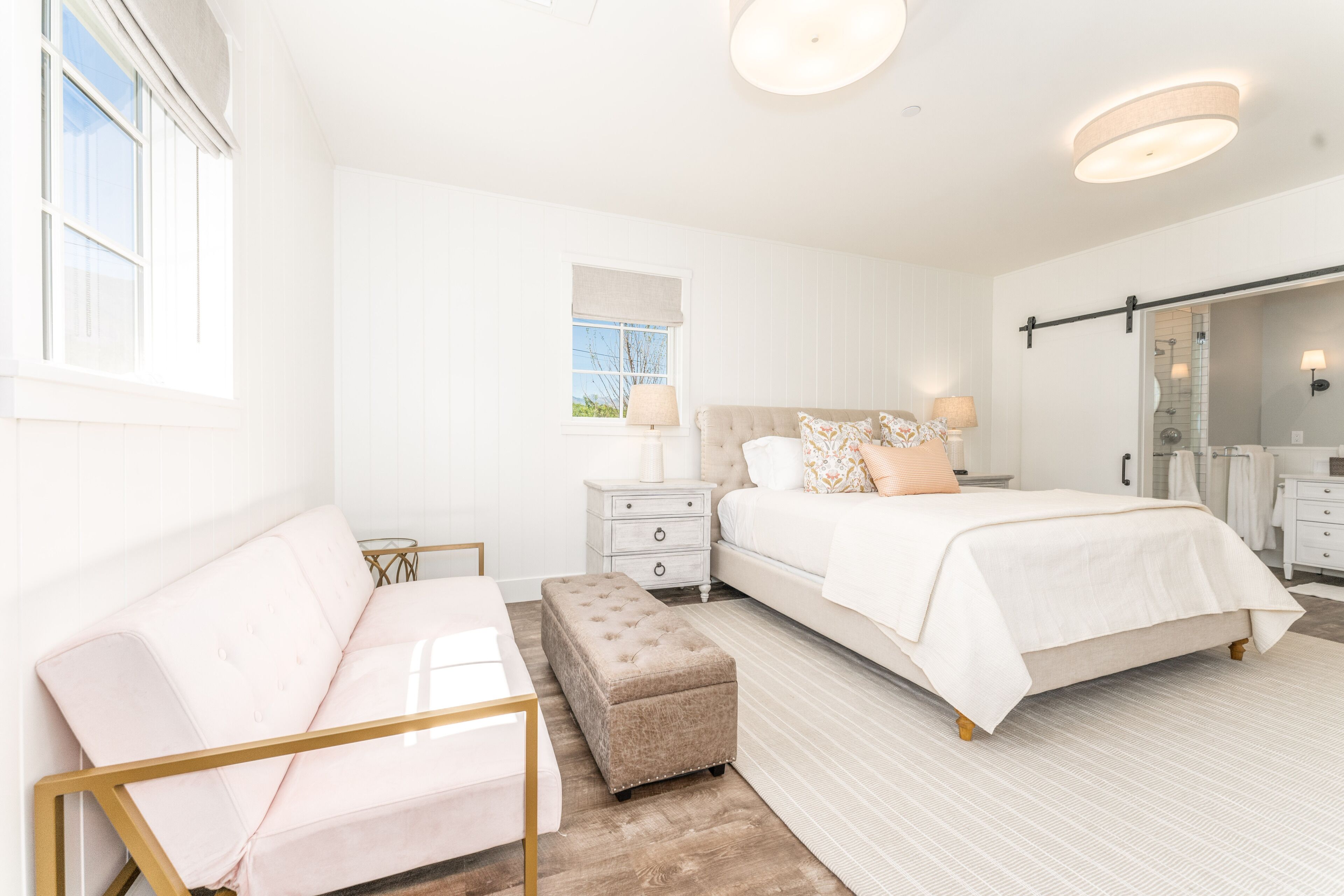 Un dormitorio con cama, mesita de noche, banco, cómoda y espejo.