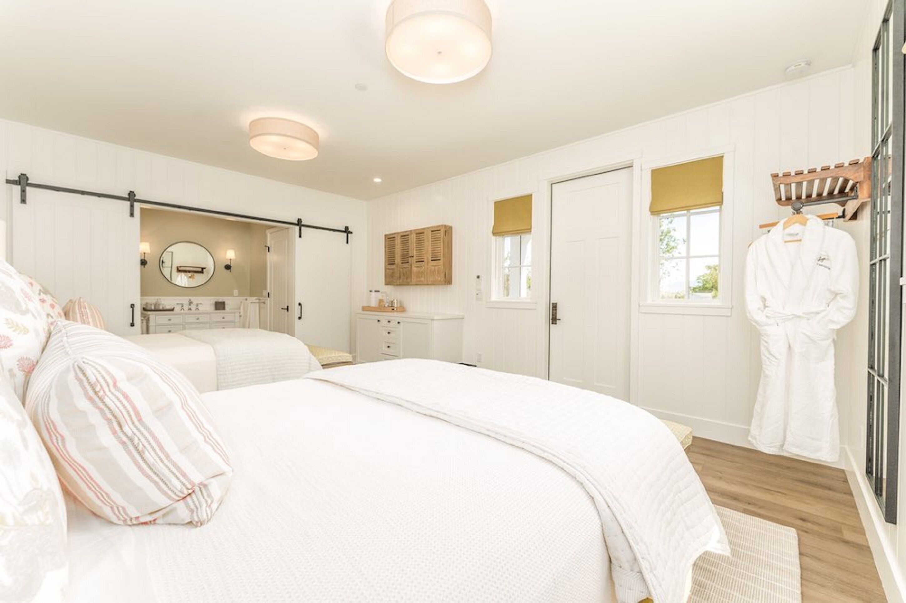 Une chambre à coucher avec un grand lit, une table de chevet, un miroir, une armoire et une fenêtre donnant sur un beau paysage.