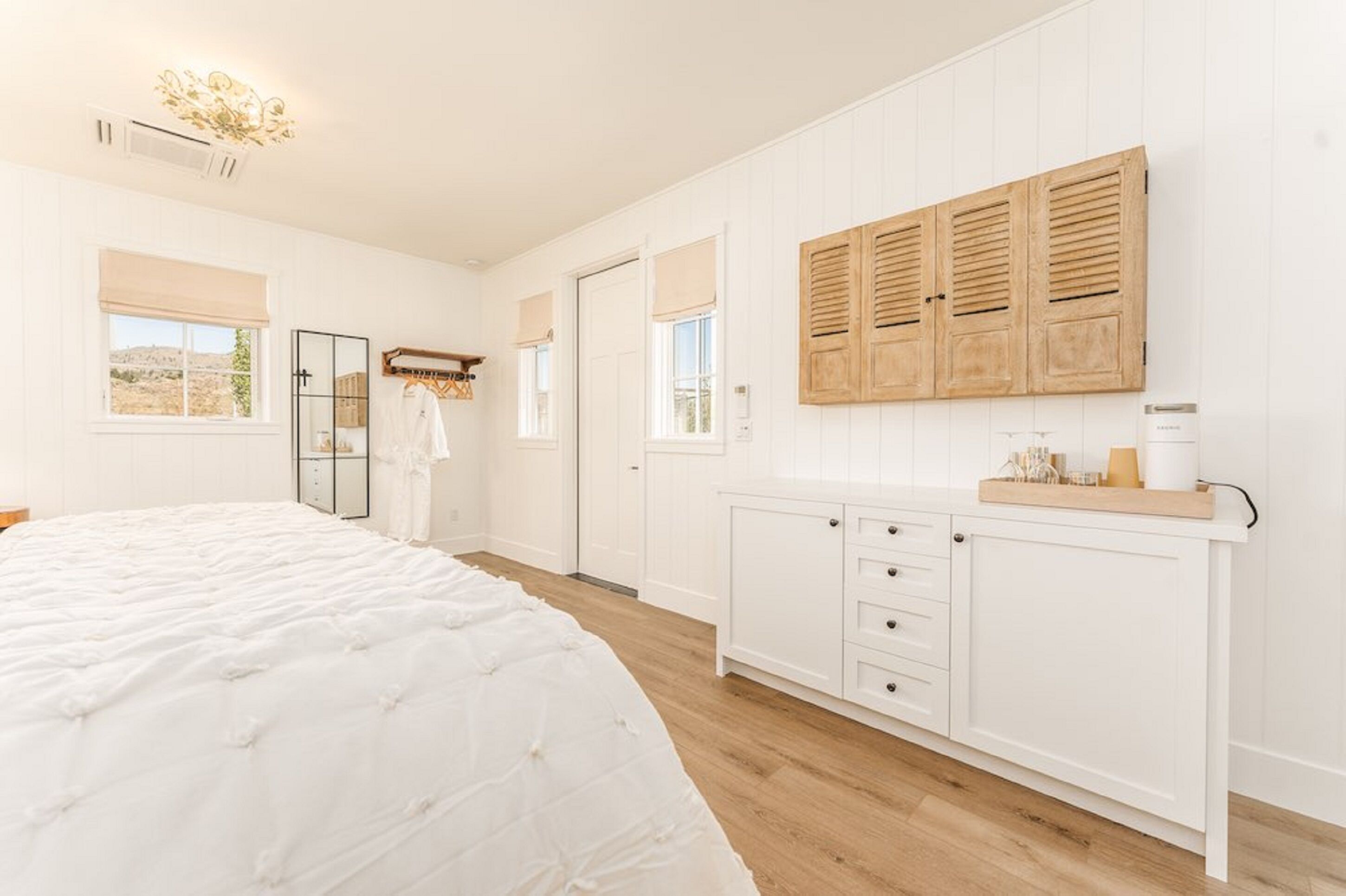 Ein Schlafzimmer mit einem großen Bett, einem Kleiderschrank, einem Spiegel und einem Fenster mit Fensterläden.