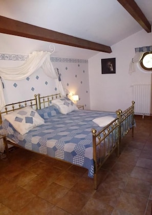 Ein Schlafzimmer mit einem Bett, einem Nachttisch, einer Wandlampe, einer Heizung und einem Fenster mit Vorhängen.