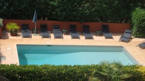 A swimming pool with lounge chairs and a potted plant. - Le Marronnier à la Bouverie (ROQUEBRUNE SUR ARGENS)