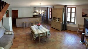 A spacious living area with a dining table, sofa, and a staircase leading to another level. - Le Marronnier à la Bouverie (ROQUEBRUNE SUR ARGENS)