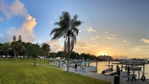 A marina with boats docked, a grassy area, and a sunset in the background.