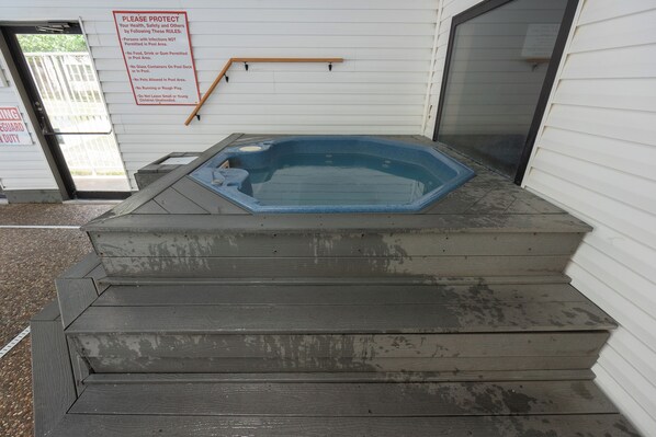 A hot tub on a set of steps with a sign listing rules.
