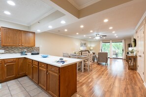 A spacious kitchen with wooden cabinets, a large island, and a dining area with chairs and a table.