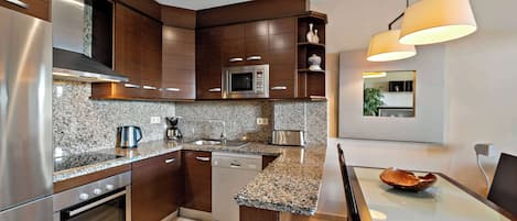 A modern kitchen with granite countertops, stainless steel appliances, and wooden cabinetry.