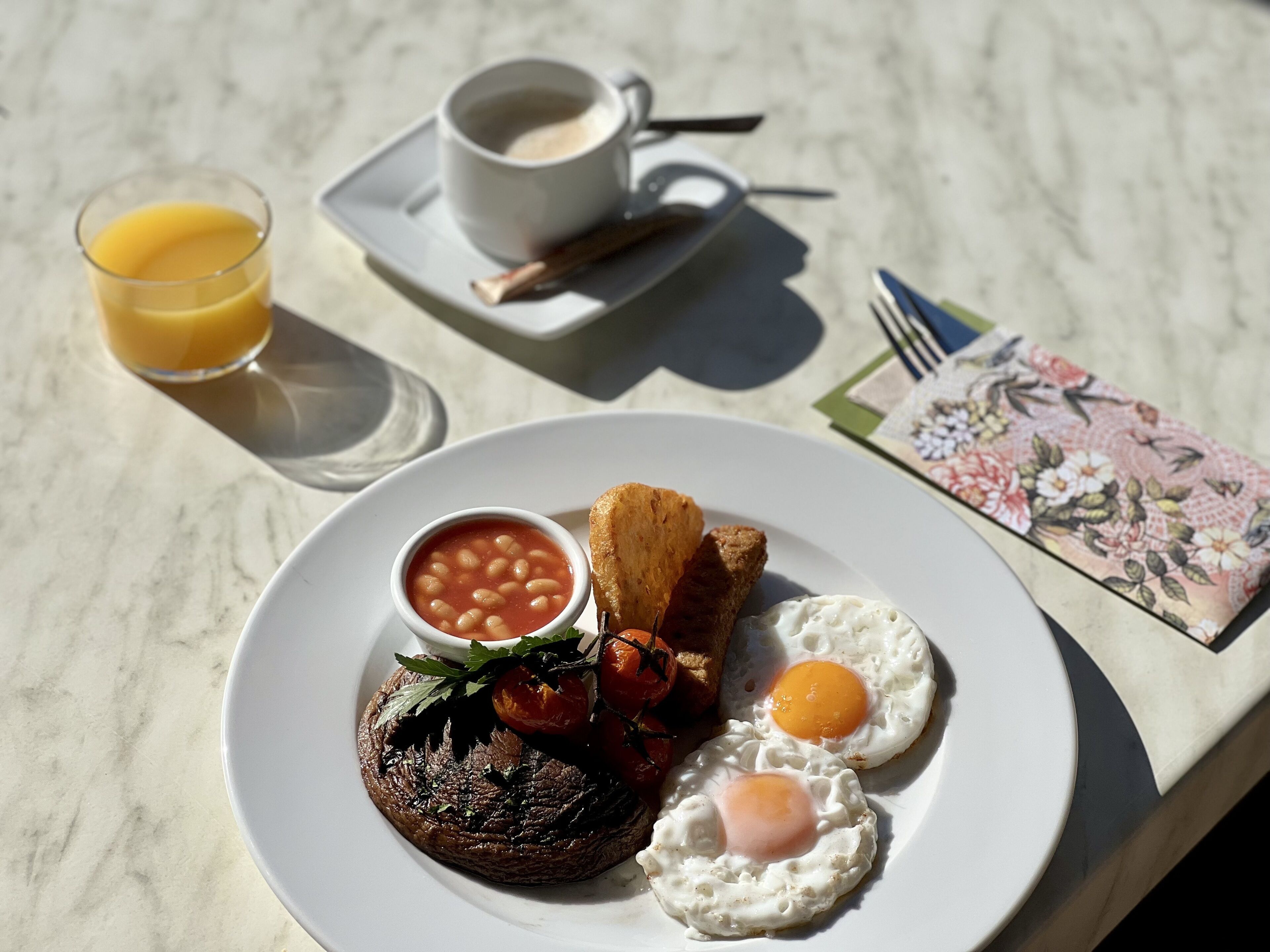 A breakfast plate with eggs, beans, toast, and tomatoes on a marble table.