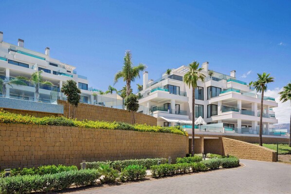 A modern hotel with multiple balconies, a brick wall, and palm trees. - Wyndham Grand Costa del Sol (Mijas)
