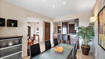 A modern kitchen with dark cabinets, a central island, and a potted plant.