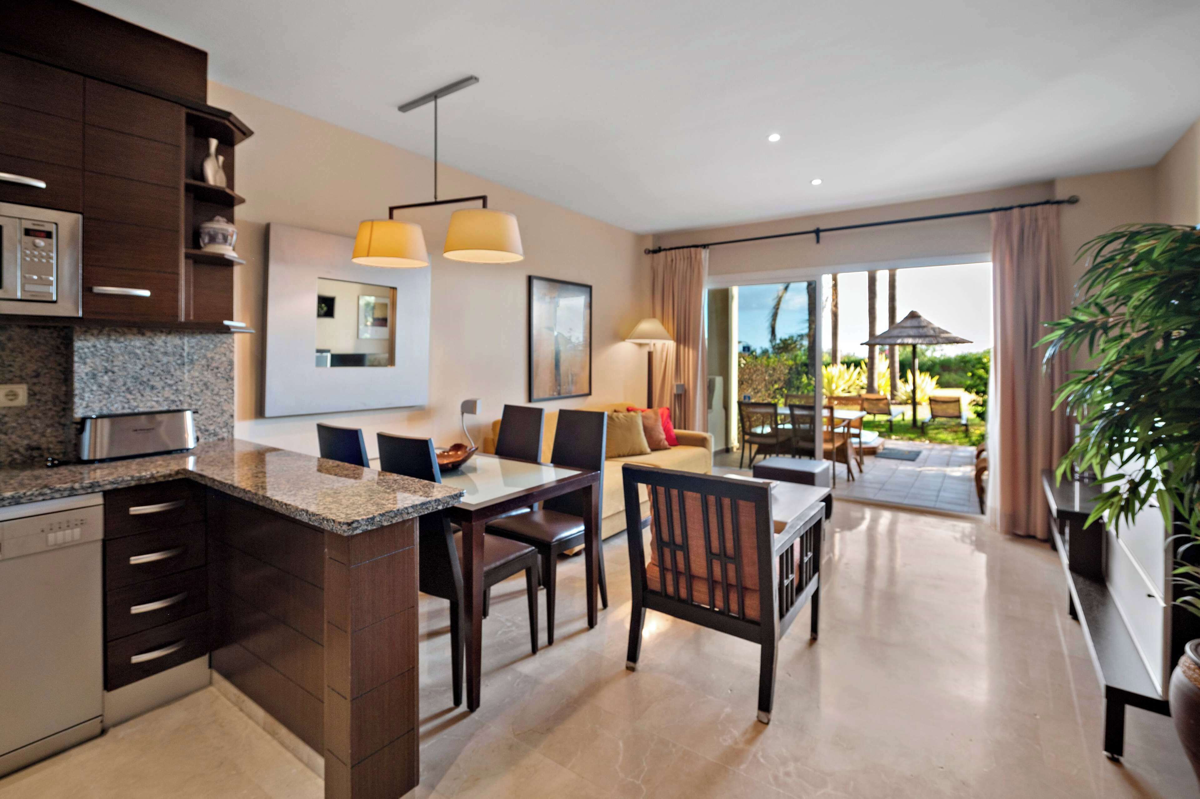 A modern kitchen with granite countertops, a dining area with a table and chairs, and a large sliding glass door leading to a patio with outdoor furniture.