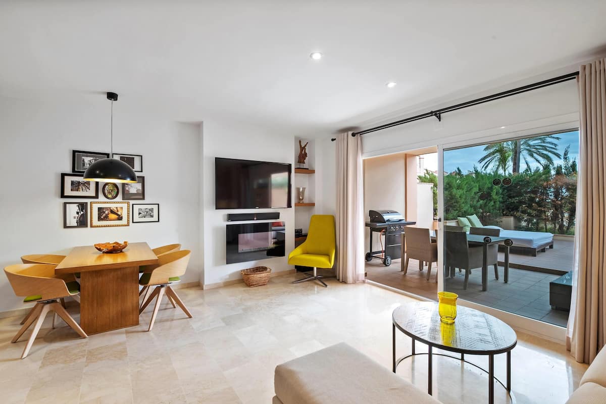 A modern living room with a dining area, a TV, and a sliding glass door to an outdoor patio.