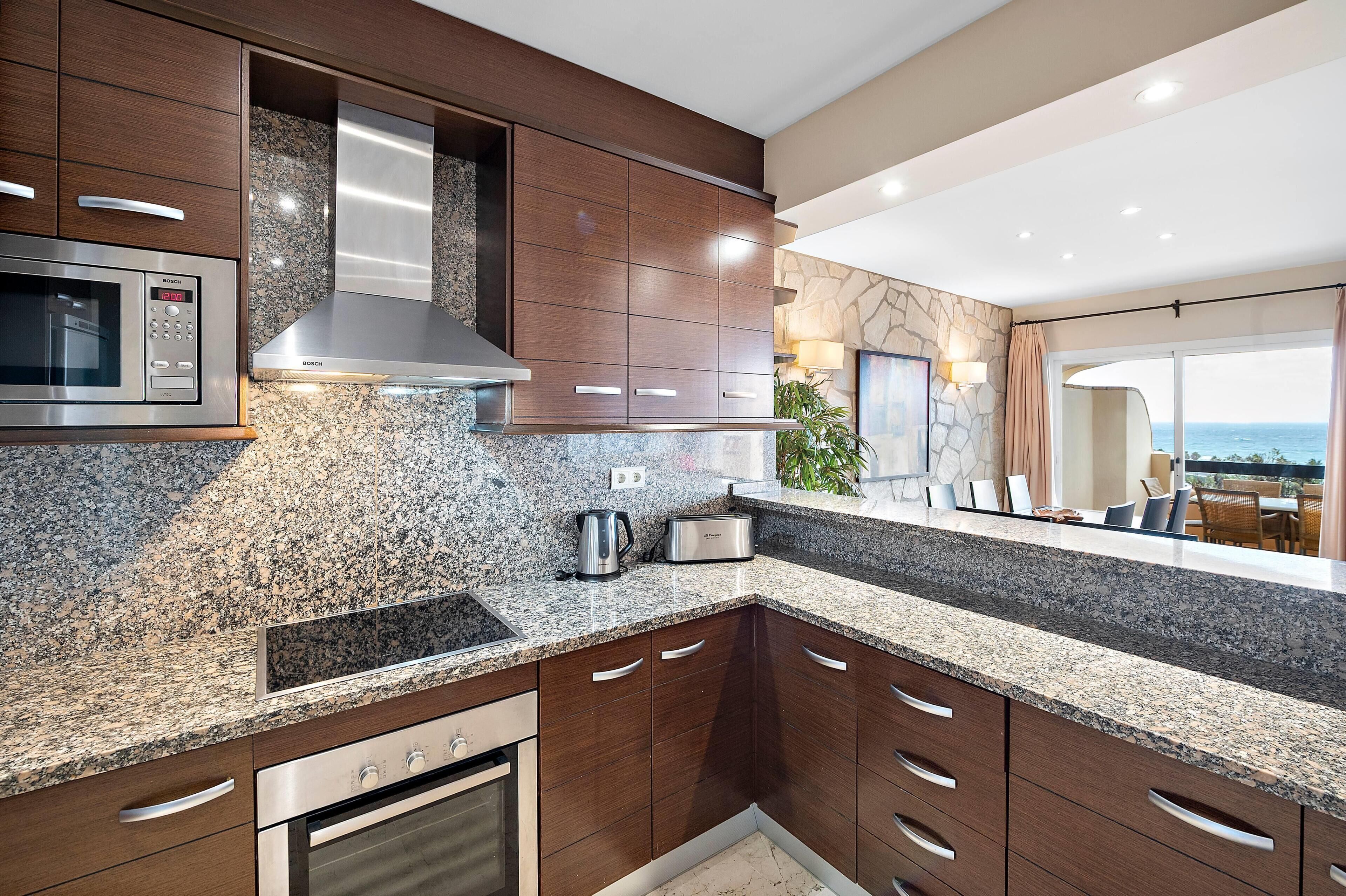 Una cocina moderna con encimeras de granito, electrodomésticos de acero inoxidable y armarios de madera.
