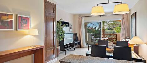 A modern hotel room with a dining area, a TV, a plant, and a balcony with a view.