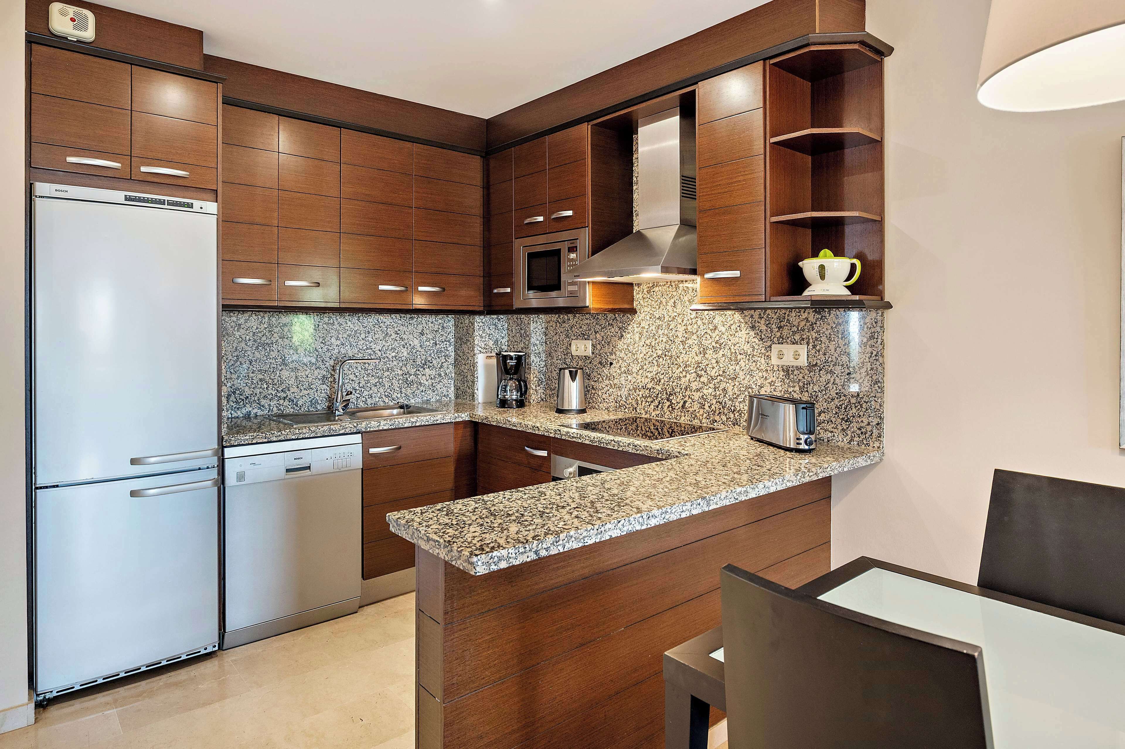 A modern kitchen with built-in appliances, granite countertops, and wooden cabinetry.