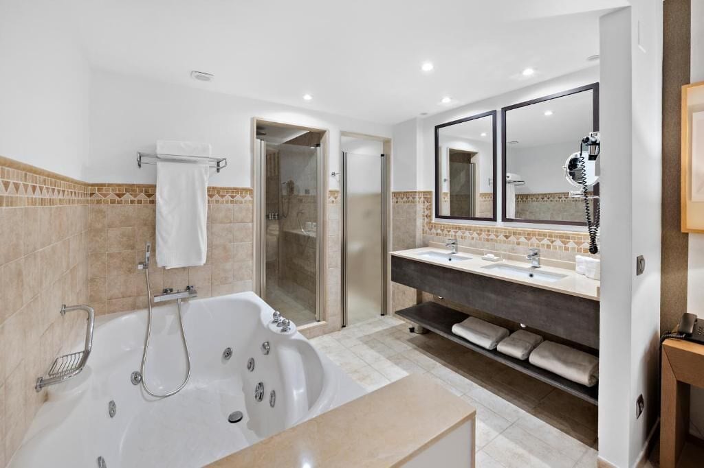 A modern bathroom with a large bathtub, a walk-in shower, and a vanity with two sinks.