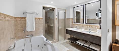 A modern bathroom with a large bathtub, a walk-in shower, and a vanity with two sinks.