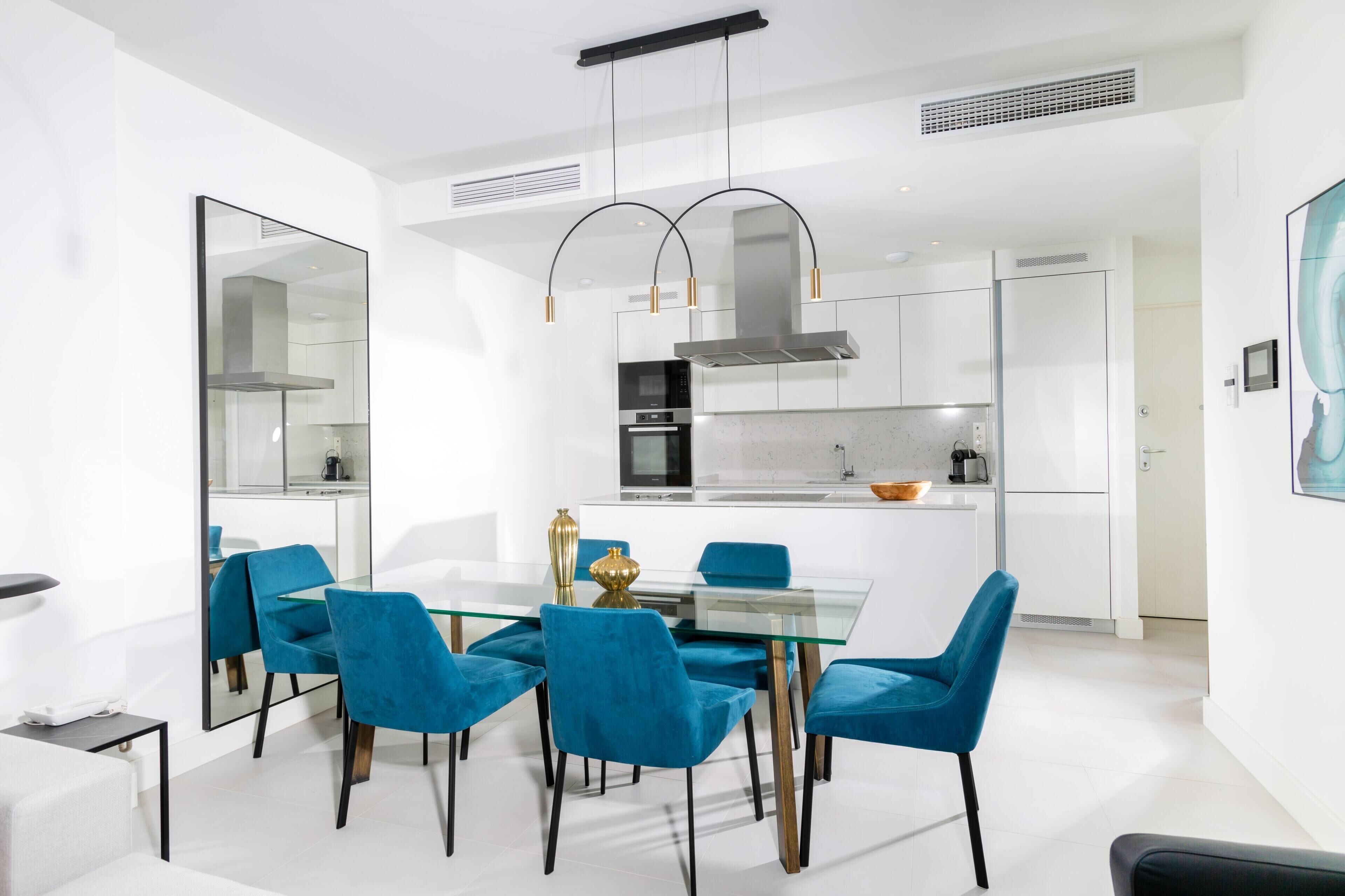 Une cuisine moderne dotée d’un îlot central, de meubles blancs et d’appareils électroménagers en acier inoxydable.