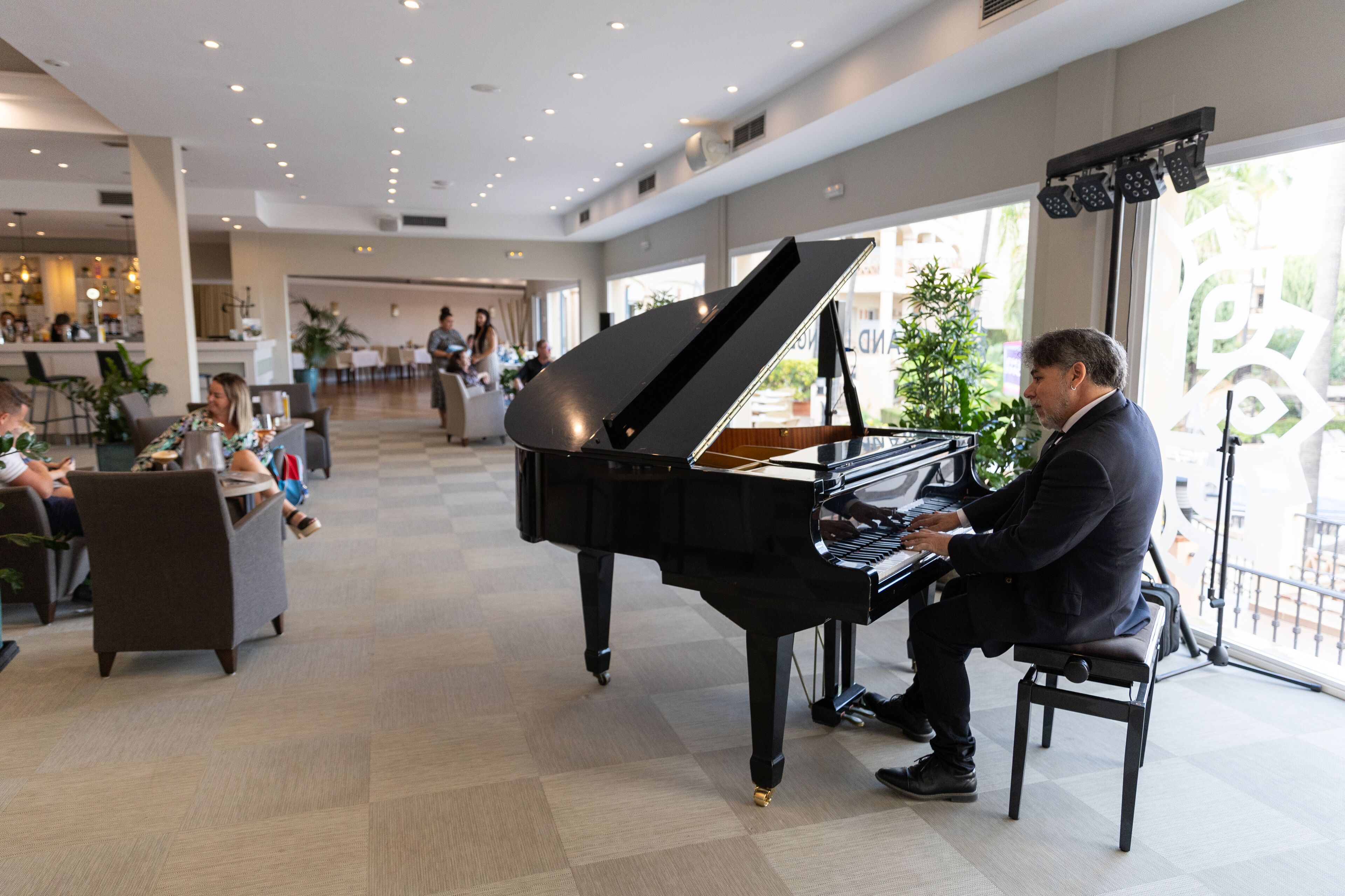 Een vleugel in een ruime, goed verlichte lobby met een modern interieur en grote ramen.