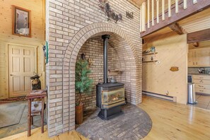Una chimenea de ladrillo con chimenea, una puerta de madera, una mesita con una silla y una planta en maceta.