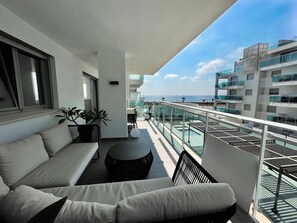 A balcony with a sofa, a small table, and a potted plant. - Apartment 'Holidays Duna Beach' Near the Beach with Sea View & Terrace (El Morche)