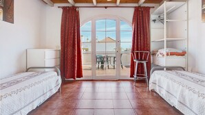 A bedroom with two beds, a ceiling fan, a sliding glass door to a balcony, and a white wardrobe. - Apartment 'Beautiful 3-Bed' with Pool, Garden and Wi-Fi (Caleta De Fuste)