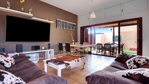 Un salon équipé d’un téléviseur à écran plat, d’un canapé, d’une table basse et d’un coin repas avec des chaises et une table.