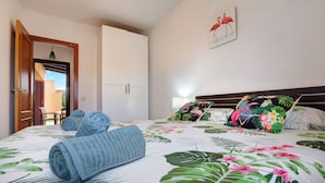 Une chambre d’hôtel avec un lit, une porte, un mur orné d’un tableau et une vue sur l’extérieur.