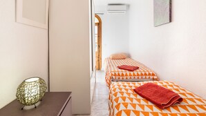Habitación de hotel con dos camas, aire acondicionado instalado en la pared y una puerta que da a otra habitación.