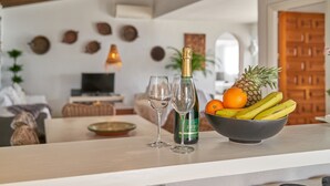 Ein Essbereich mit einem Tisch, gedeckt mit zwei Weingläsern, einer Flasche Dubonnet und einer Obstschale.