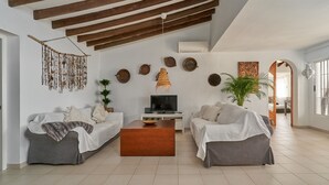 Ein Wohnzimmer mit zwei Sofas, einem Couchtisch, einem Fernseher und Wanddekorationen.
