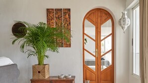 Ein Zimmer mit Holztür, einem Blumentopf, einer Holzkiste und einem an der Wand befestigten Kunstwerk.