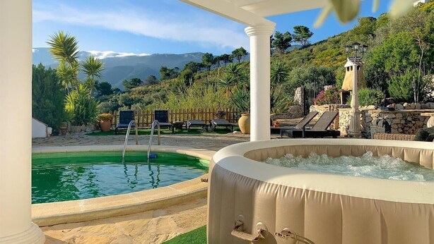 Ein Poolbereich mit Whirlpool, Liegestühlen und einer Steinmauer mit einer Lampe.