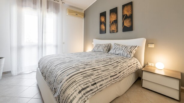 Un dormitorio con cama, mesita de noche y decoración en la pared.