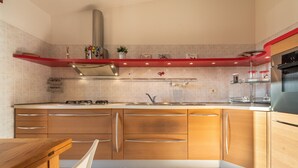Una cocina moderna con armarios de madera, extractor de acero inoxidable y salpicadero rojo.