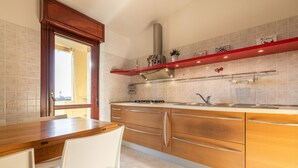Una cocina con armarios de madera, una campana extractora de acero inoxidable y un estante rojo sobre la encimera.