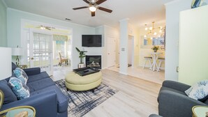 Un salon avec un canapé, un pouf et un téléviseur à écran plat.