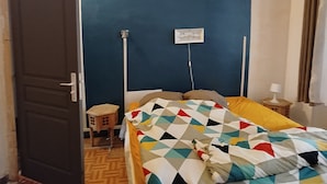 Quarto com cama, mesa de cabeceira, tomada e porta.