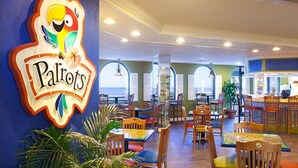 A restaurant interior with multiple tables and chairs, a large sign on the wall, and large windows.