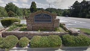 Un letrero para Turtle Creek Villas, con un arco de piedra y follaje a su alrededor.