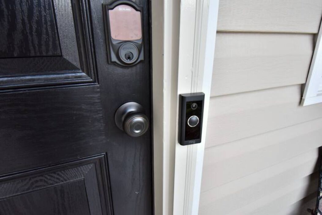 A black door with a keyhole and a small, rectangular, pink-colored panel above it.